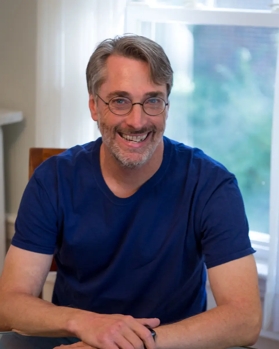 man with glasses and dark blue shirt smiling