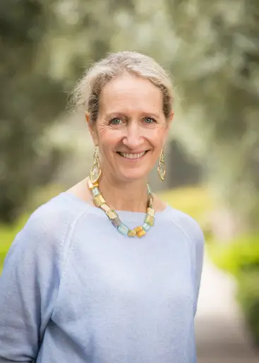 woman in blue sweater and earrings smiling